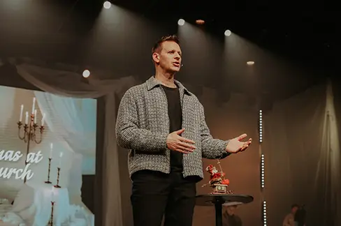 pastor standing on stage hands folded