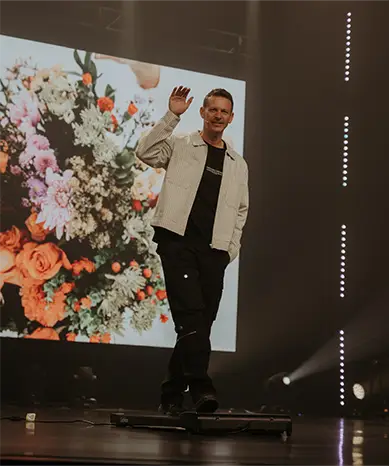 three people singing on stage overlooking audience