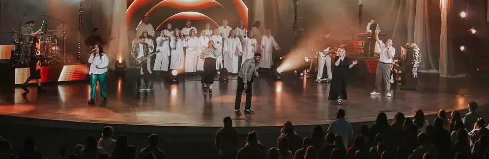 three people singing on stage overlooking audience