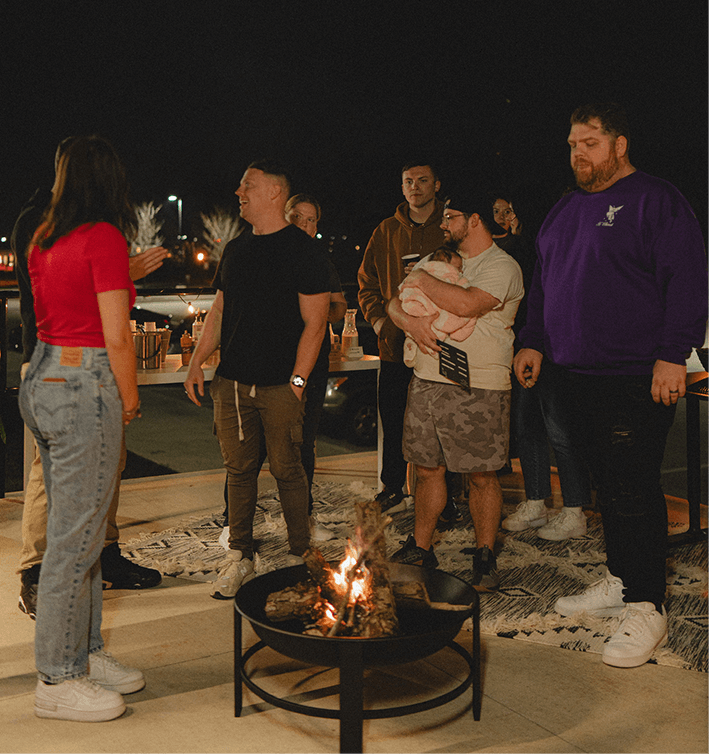 people standing outside at night around a firepit